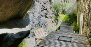 Außenterrasse zwischen dem Gebäude und dem Berg, an den das Gebäude angelehnt ist.