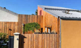 Urbanes Tiny House in Vaulx-en-Velin. Es ist ein kleines Haus mit einer Fassade und einem Holzzaun um seinen Außenbereich.