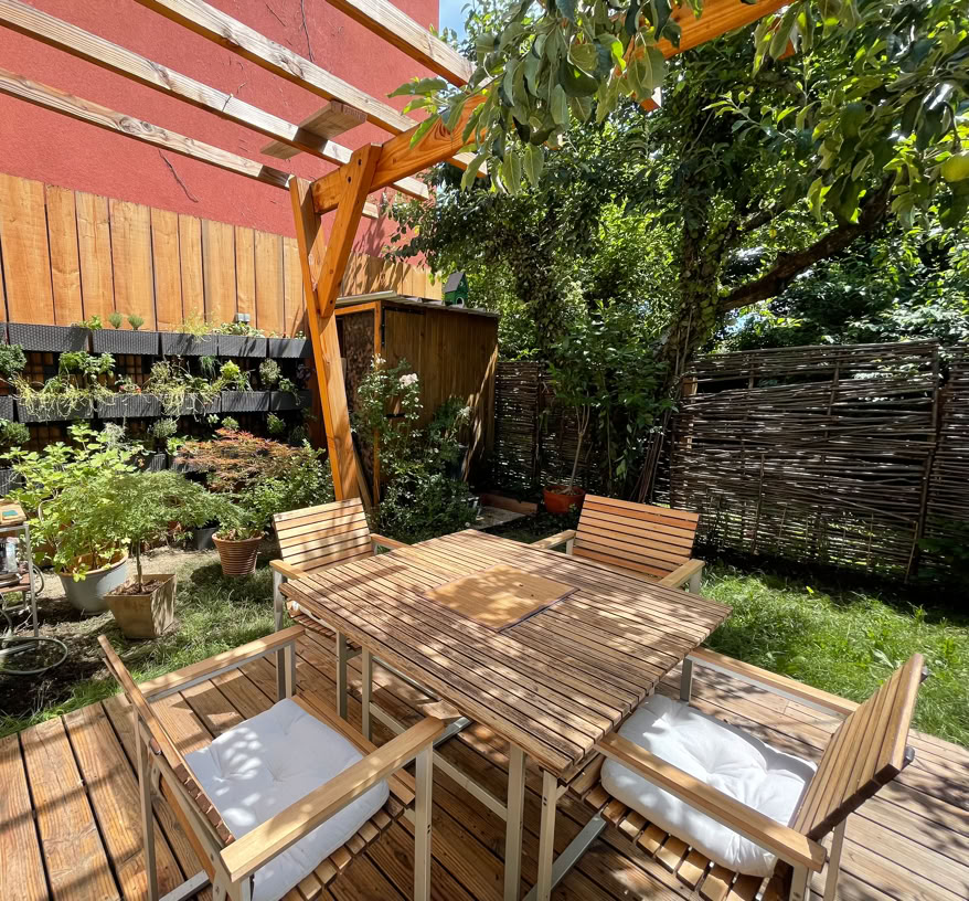 Holzterrasse im Freien mit Pergola und Bepflanzung.