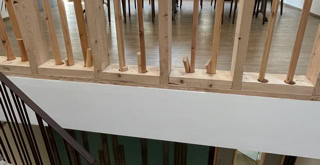 Photo des rambardes des escaliers, l'une en métal pour les marches et l'autre en bois et jusqu'au plafond pour le palier.