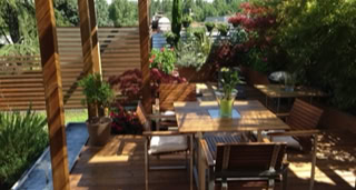 Wooden terrace and pergola with vegetation.