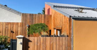 Wooden facade of the tiny house, wooden fence around the outside area.