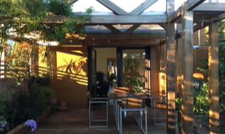 Außenterrasse mit Pergola und umgeben von Vegetation.