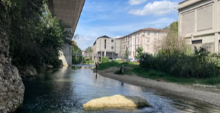 Photo of the river and the Vaganay gymnasium, a former industrial building converted into a gymnasium using a concrete extension.