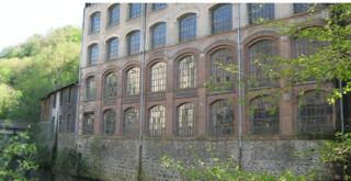 Exterior facade of an unoccupied industrial building overlooking the River Gère.