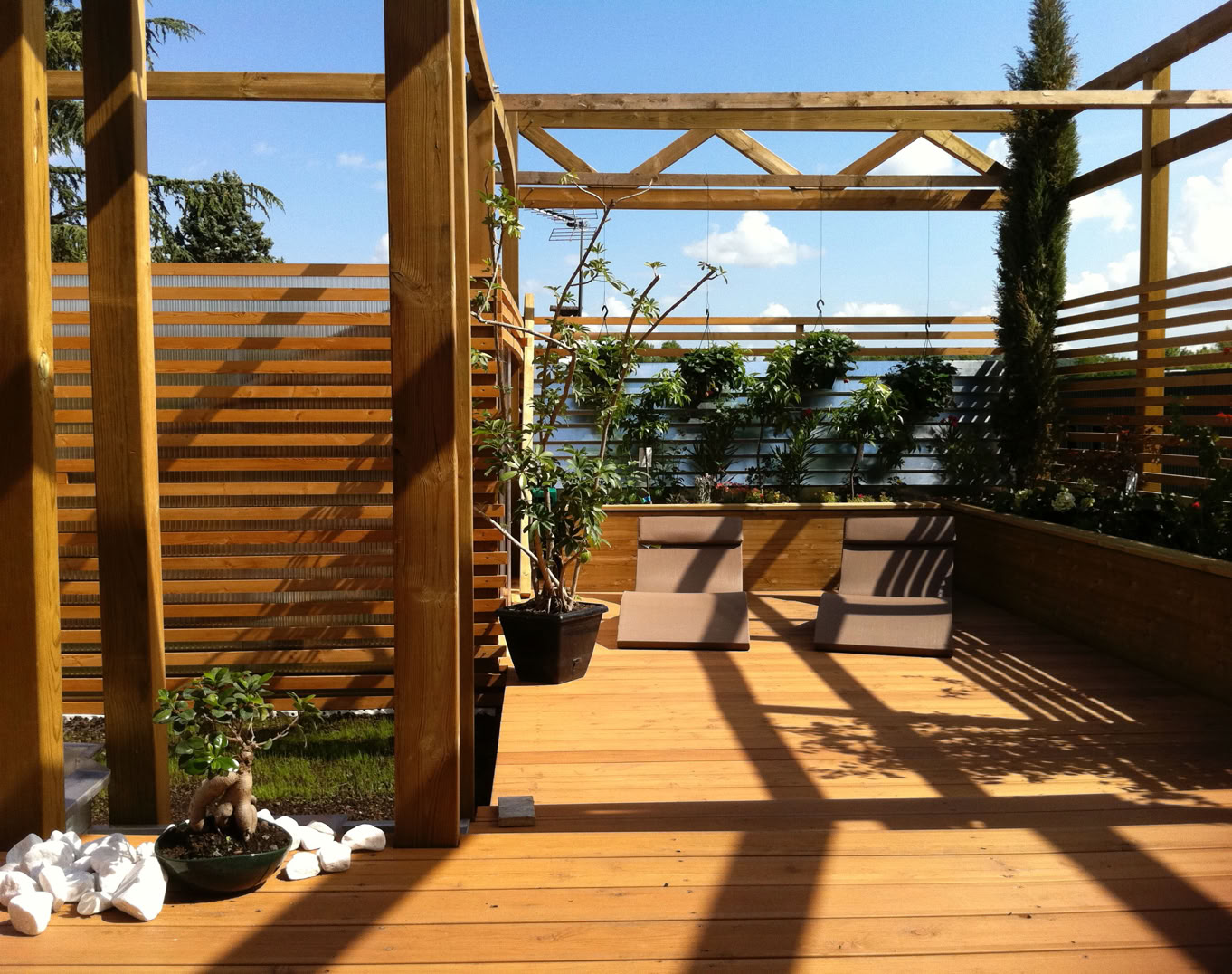 Photo d'une terrasse bois avec pergolas et végétation d’un projet réalisé par l'agence.